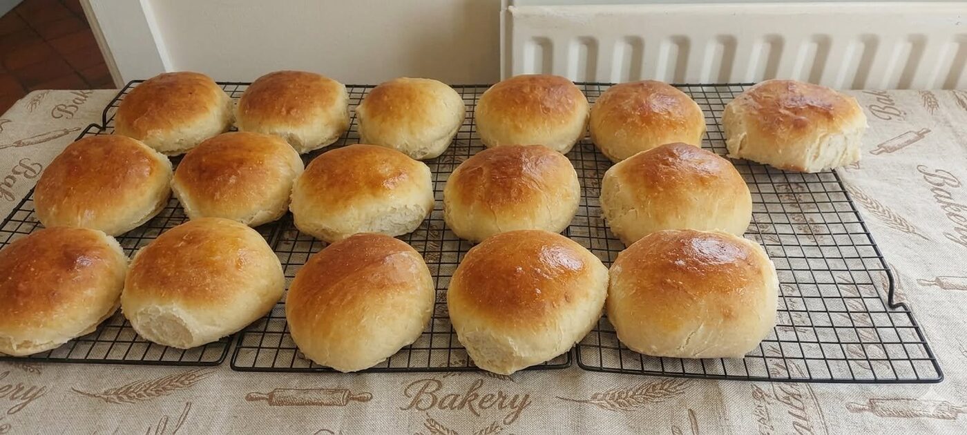 A batch of golden bread rolls cooling